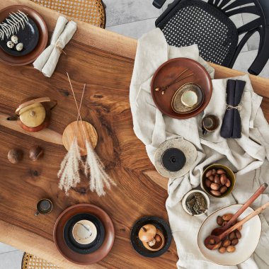 Ahşap ceviz masası, retro sandalyeler, sofra takımı, tabaklar, masa örtüsü, çaydanlık, yemek, dekorasyon ve zarif aksesuarları olan şık bir iç dizayn. Beton zemin. Şablon. Üst görünüm.