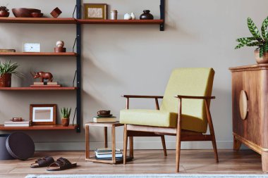 Tasarım koltuğu, ahşap kitaplık, resim çerçeveleri, bitki, halı, terlik, dekorasyon ve ev dekorasyonuyla retro oturma odasının şık kompozisyonu. Şablon.