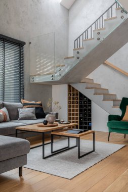 Oturma odasının iç kısmının şık kompozisyonu. Gri kanepe, yeşil kadife koltuk, sehpa ve minimalist kişisel aksesuarlar. Modern ev dekorasyonu. Şablon.