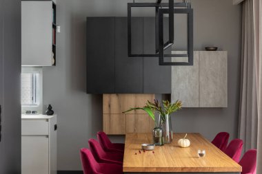 Yemek odasının iç dekorasyonunun zarif detaylarını yakından incele. Kadife sandalyeler, ahşap masa ve güzel aksesuarlar. Açık alan. Beton duvarlar. Modern ev dekorasyonu. Şablon.