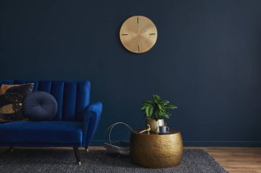 Şık oturma odası kompozisyonu kadife mavi kanepe, altın yan masa ve zarif ev dekoru. Koyu mavi duvar kağıdı. Şablon. Boşluğu kopyala.