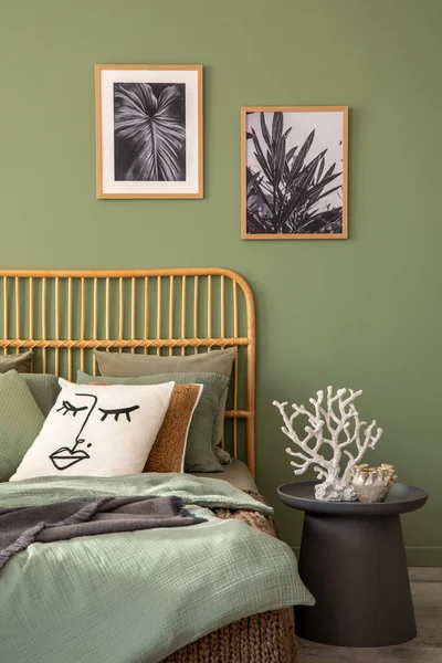 Elegant bedroom interior design with mock up poster frames, bamboo bed, modern bedclothes, side table and stylish accessories. Eucalyptus wall. Template. Copy space.