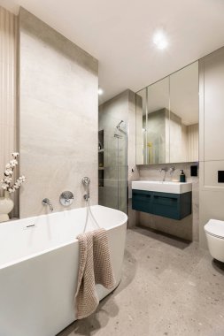 Lamella duvarlı, modern, parlak bir banyo. Gümüş musluk ve kahverengi havluyla büyük beyaz bir banyo. Karanlık dolabı ve morgu olan lavabo.. 