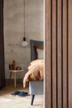 Modern yatak odasının iç kısmının şık bir kompozisyonu. Yatak, yaratıcı lamba ve zarif kişisel aksesuarlar. Beton duvar. Kahverengi çarşaflar. Minimalist erkeksi kavram. Şablon