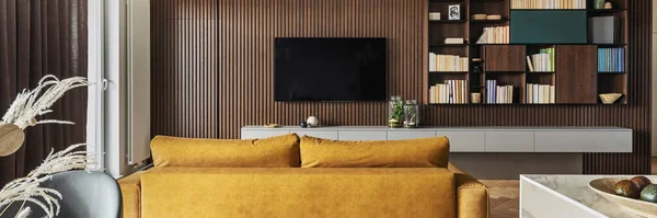 Creative and modern vintage living room interior design with yellow sofa and lamella wall with tv and bookcase. Herringbone parquet with chest of drawers, brown curtain in windows. Template.
