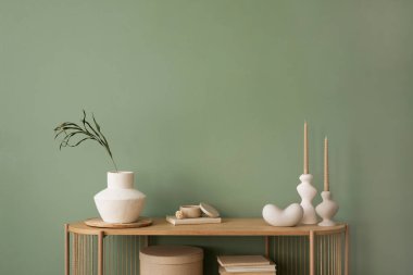 Şık bir oturma odası iç tasarımı, ahşap çekmeceler, bej vazo ve yaratıcı ev aksesuarları. Bilge yeşil duvar. Uzayı kopyala Şablon. 