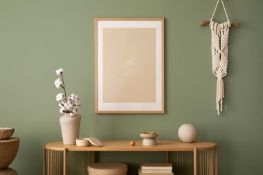 Stylish living room interior design with mock up poster frames, macrame, wooden chest of drawers, beige vase and creative home accessories. Sage green wall. Template. 