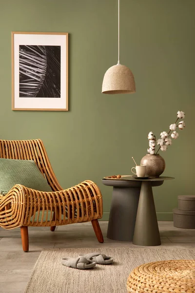 Stylish living room interior design with rattan chair, mock up potser frame, side table and creative accessories. Sage green wall. Template. Copy space