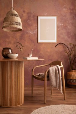 Stylish boho vintage dining room interior with poster mock up. Round table with rattan chair, vase with dried flowers. Brown wall and rattan lamp. Mock up poster. Template. 