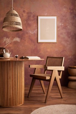 Stylish boho vintage dining room interior with poster mock up. Round table with rattan armchair, vase with dried flowers and cup. Brown wall and rattan lamp. Mock up poster. Template. 