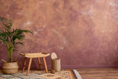 Stylish boho vintage dining room interior with copy space,  rattan stool, basket with plant. and personal accessories. Brown wall. Home decor. Template. 