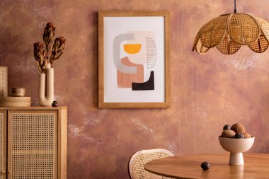 Stylish boho vintage dining room interior with poster mock up. Round table with rattan chair, commode and flowers. Brown wall and rattan lamp. Mock up poster. Template. 