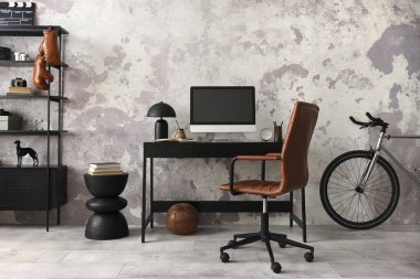 Concrete interior of home office with black desk, brown armchair, computer screen, office accessories and lamp. Rack with personal accessories. Home decor. Template. 