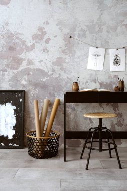 Concrete interior of home office with black desk, office accessories, lamp. Rack with personal accessories. Home decor. Template. 