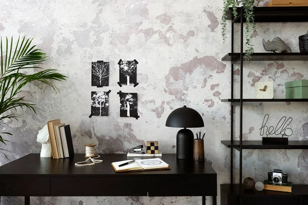 Concrete interior of home office with black desk,  lamp, image, office accessories and plants. Rack with personal accessories. Home decor. Template.