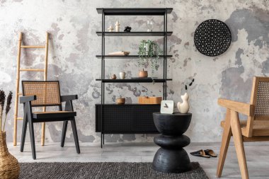The stylish composition of wabi sabi interior with black rack, rattan armchair, carpet, coffee table and personal accesoories. Grey concrete wall. Home decor. Template. 