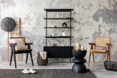The stylish composition of wabi sabi interior with black rack, rattan armchair, carpet, coffee table and personal accesoories. Grey concrete wall. Home decor. Template. 
