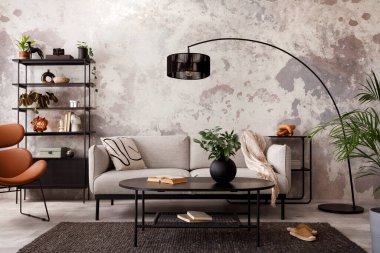 The stylish compostion at living room interior with design gray sofa, armchair, black coffee table, lamp and elegant personal accessories. Loft and industrial interior. Template.