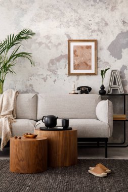 The stylish compostion at living room interior with design gray sofa, woooden coffee table, poster and elegant personal accessories. Loft and industrial interior. Template. 