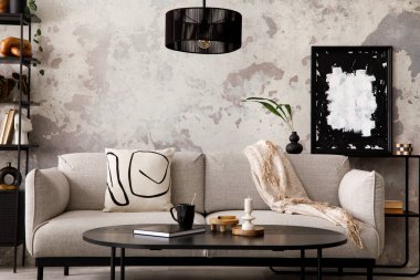 The stylish compostion at living room interior with design gray sofa, armchair, black coffee table, lamp and elegant personal accessories. Loft and industrial interior. Template.