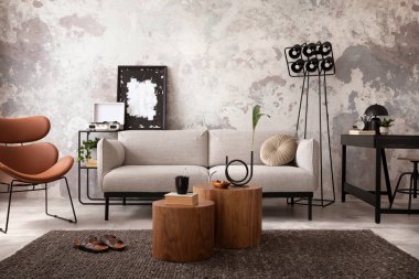 The stylish compostion at living room interior with design gray sofa, wooden coffee table, desk and elegant personal accessories. Loft and industrial interior. Home decor. Template.