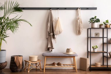 The stylish composition of cosy entryway with grey bench, black consola, hanger and plant. Beige wall. Home decor. Template. 