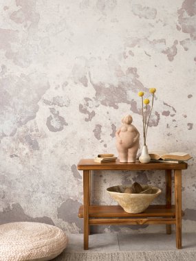 The stylish ethnic composition at living room interior with copy space, beige bowl, bench and elegant personal accessories. Grey concrete wall. Cozy apartment. Home decor. 