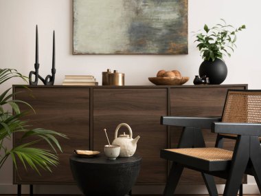 The stylish compostion at living room interior with mock up, wooden commode, rattan chairs and elegant personal accessories. White wall with modern image. Cozy apartment. Mock up poster