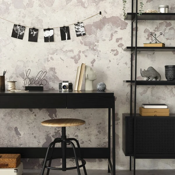 Concrete interior of home office with black desk, office accessories, lamp. Rack with personal accessories. Home decor. Template.