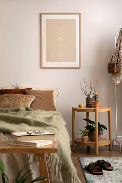 Stylish composition of cozy bedroom with mock up, beige bedding, and wooden coffee table. Mock up poster with wooden frame. Home decor. Template.