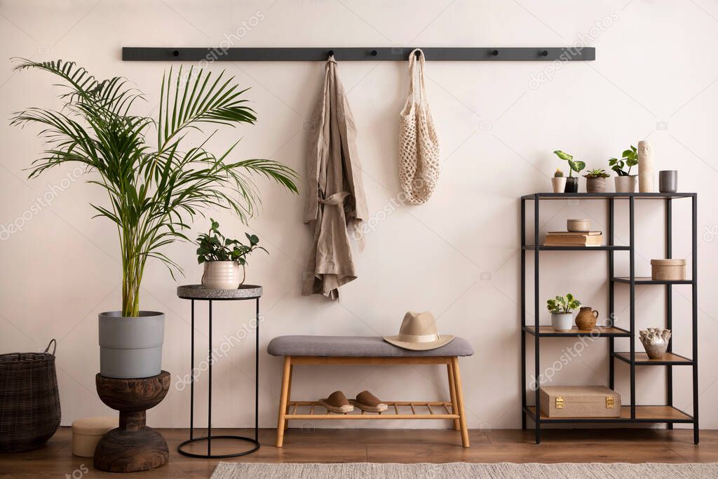 The stylish composition of cosy entryway with grey bench, black consola, hanger and plant. Beige wall. Home decor. Template. 