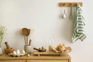 Interior design of kitchen space with rattan commode, milk, eggs, food and kitchen accessories in boho home decor.  Template. 