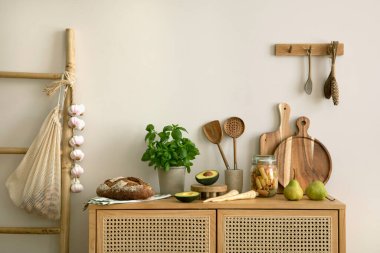 Interior design of kitchen space with rattan commode, ladder, herbs, vegetables, food and kitchen accessories in modern home decor. Template. 