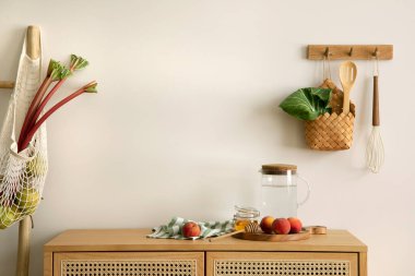 Interior design of kitchen space with copy space, rattan commode,  ladder, rhubarb, vegetables, food and kitchen accessories in modern home decor.  Template. 