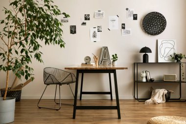 The stylish composition of cozy office interior with metal chair, wooden table, plants poster and personal accessories. Home decor. Template. 