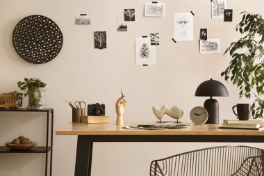 The stylish composition of cozy office interior with metal chair, wooden table, plants poster and personal accessories. Home decor. Template. 