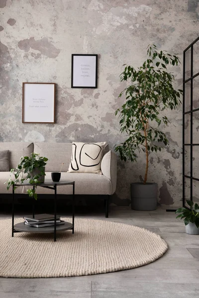 The stylish compostion at living room interior with design gray sofa, coffee table, plant, hanger, lamp and elegant personal accessories. Loft and industrial interior. Mock up poster. Template.