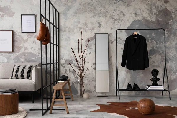 The stylish compostion at living room interior with design gray sofa, bench, coffee table, hanger, lamp and elegant personal accessories. Loft and industrial interior. Mock up poster. Template.