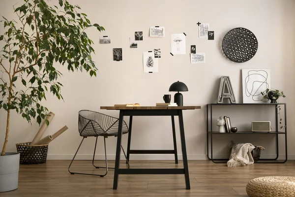 The stylish composition of cozy office interior with metal chair, wooden table, plants poster and personal accessories. Home decor. Template. 