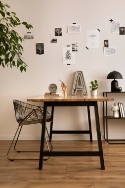 The stylish composition of cozy office interior with metal chair, wooden table, plants poster and personal accessories. Home decor. Template. 