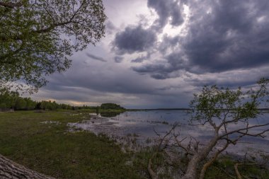 Baharın başlarında göl manzarası. Dramatik gökyüzü suya yansıyor.