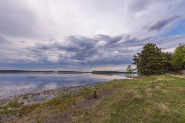 Baharın başlarında göl manzarası. Dramatik gökyüzü suya yansıyor.