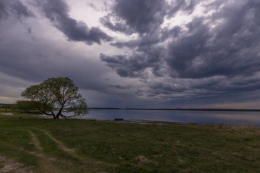 Baharın başlarında göl manzarası. Dramatik gökyüzü suya yansıyor.