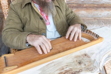 Etnik giyimli bir adam antik bir müzik aleti çalar. Sakallı bir adam, bir ormancı bir ev inşa etti ve bir ilahiyi canlandırıyor.. 