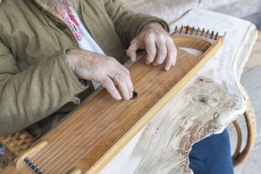 Etnik giyimli bir adam antik bir müzik aleti çalar. Sakallı bir adam, bir ormancı bir ev inşa etti ve bir ilahiyi canlandırıyor.. 