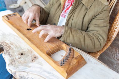 Etnik giyimli bir adam antik bir müzik aleti çalar. Sakallı bir adam, bir ormancı bir ev inşa etti ve bir ilahiyi canlandırıyor.. 