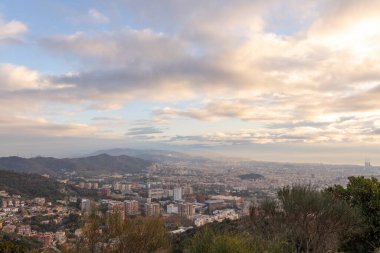 Sabahın erken saatlerinde tepeden Barselona 'nın resimli manzarası. Bulutların arasından güneş ışınları. Şehrin üzerinde dramatik bir gökyüzü. İspanya, Barselona 'da sonbahar.