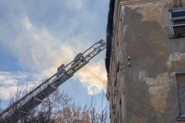 İtfaiyeci, itfaiye arabasının patlamasıyla çalışır. Gökyüzü arka planında itfaiyeci. Tarihi merkezde eski binayı yakmak