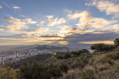 Sabahın erken saatlerinde tepeden Barselona 'nın resimli manzarası. Bulutların arasından güneş ışınları. Şehrin üzerinde dramatik bir gökyüzü. İspanya, Barselona 'da sonbahar.