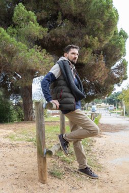 Sokakta poz veren sakallı yakışıklı bir adam. Sıcak giysili şık genç adam. Güneşli bir günde Hipster doğada.